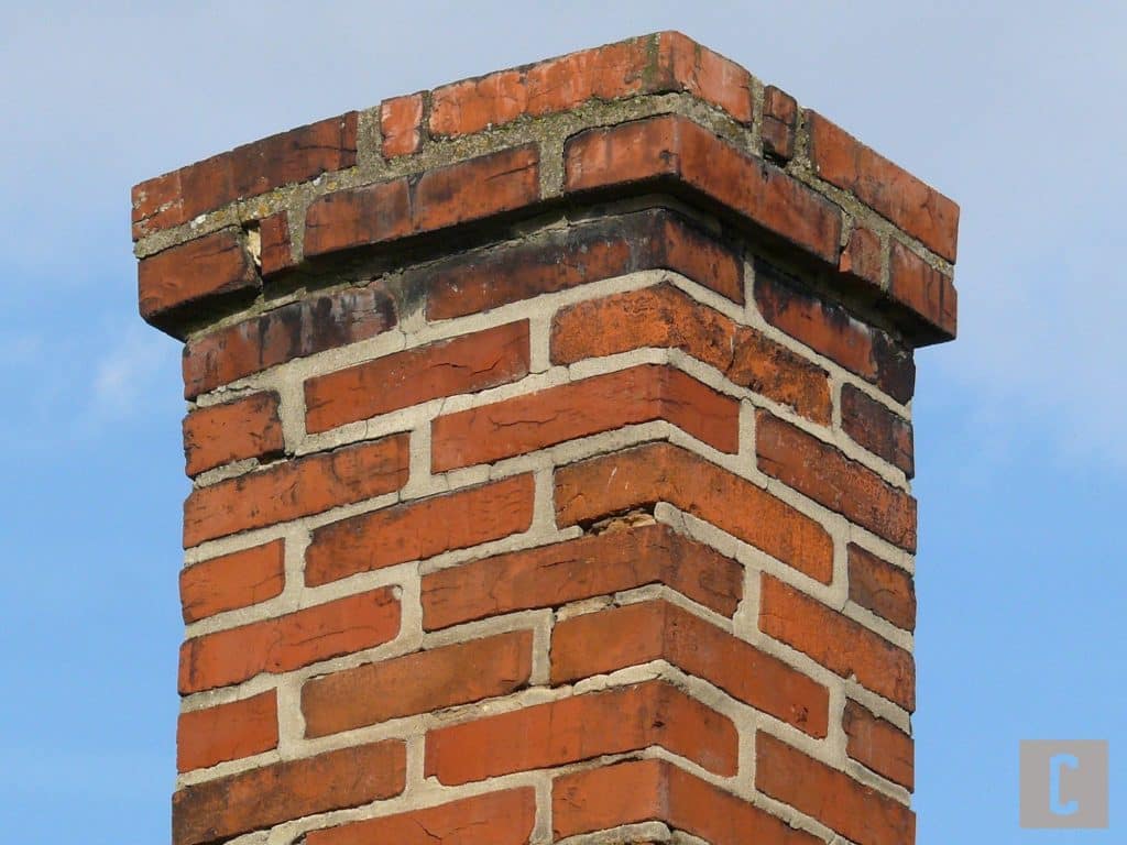 Cheminée de brique endommagée créant une infiltration d'eau par une toiture. 